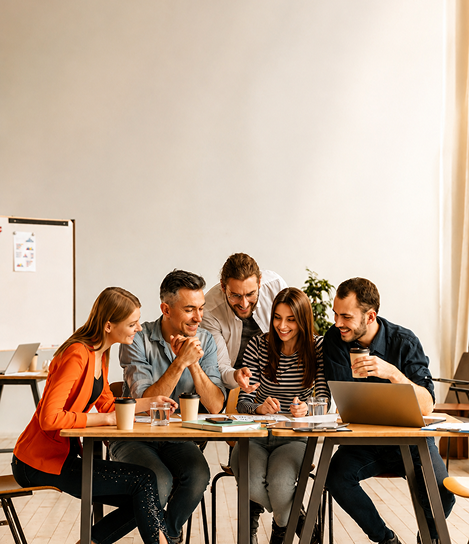 A group of people sitting around a table with a laptop.