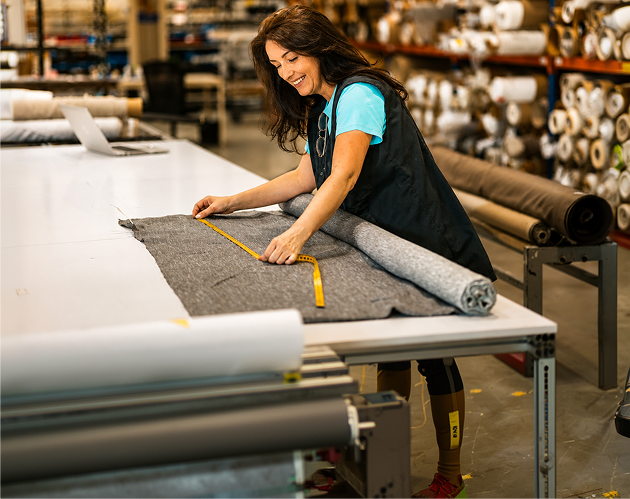 A woman in a factory working on a piece of fabric.