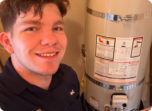 Young man smiling next to a grey water heater.