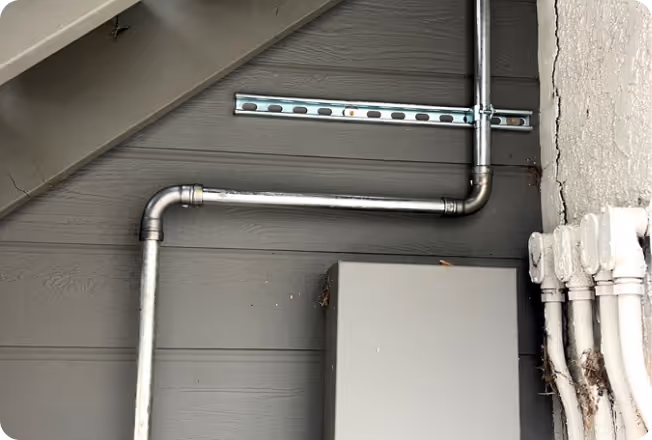 Metal gas pipes installed on a gray wooden wall.