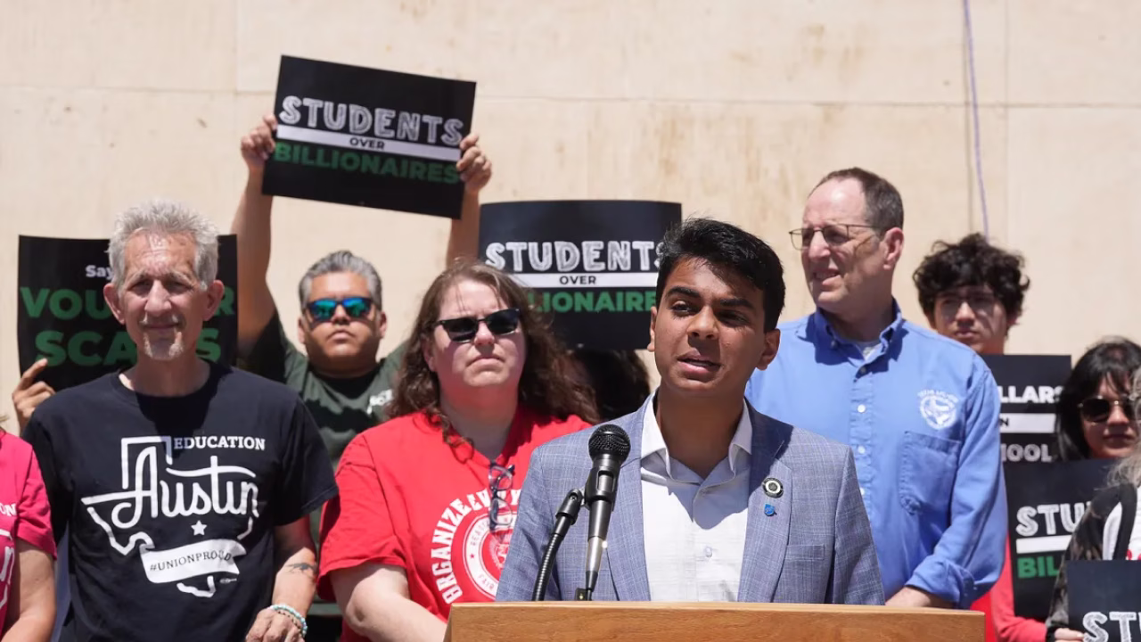 Smiling young man standing outside the White House with rainbow-colored columns in the background.
