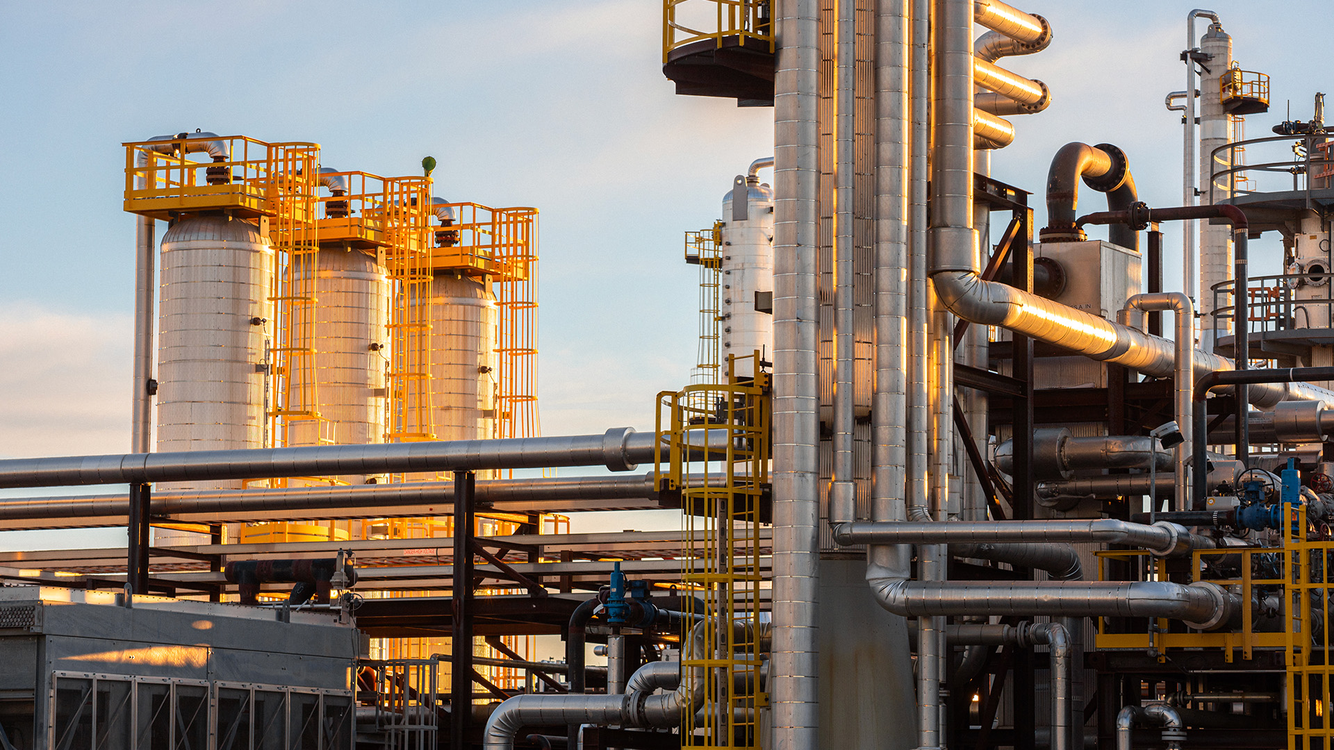 Gas processing facility with steel columns and pipe racks at sunset
