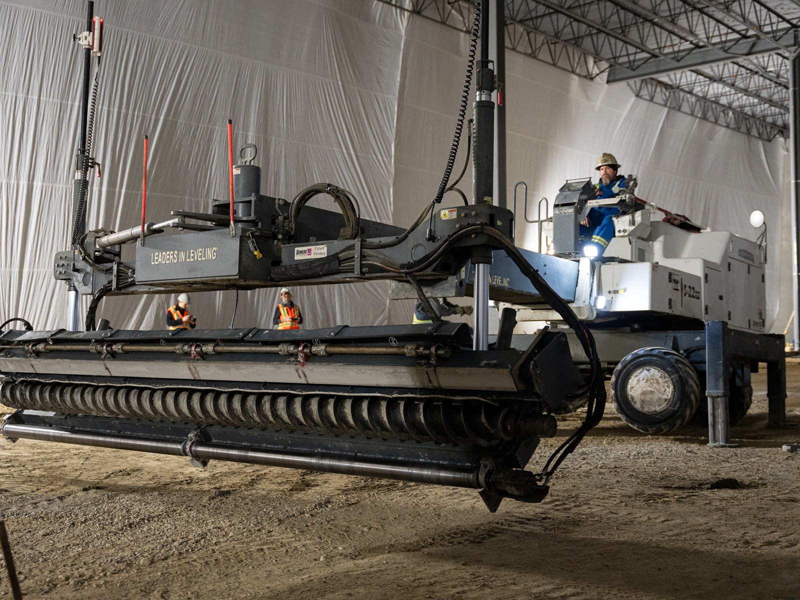 The laser-guided screed and its operator inside the tented slab area at Starfield