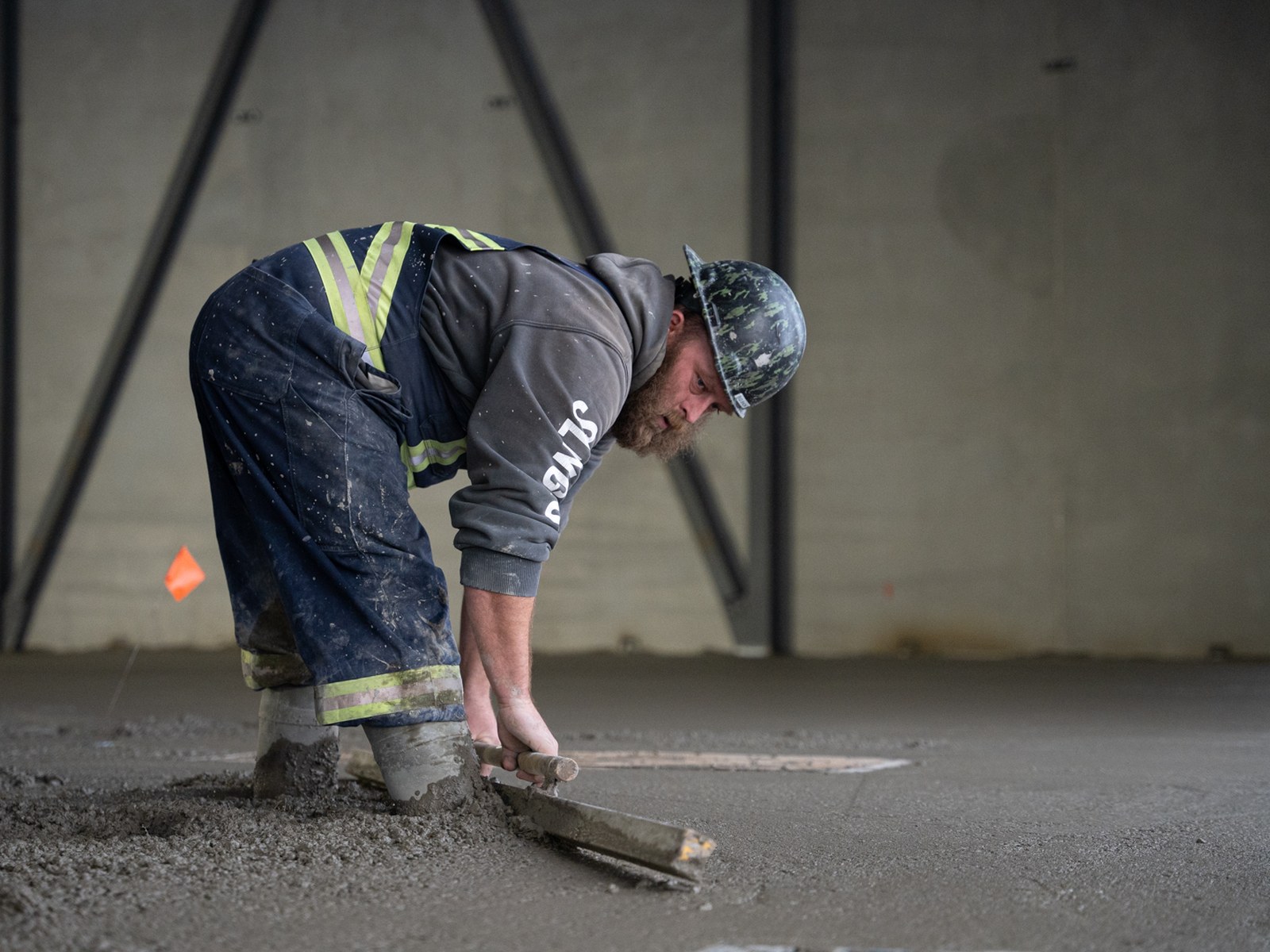 A finisher smoothing the slab edge with a hand trowel at Starfield