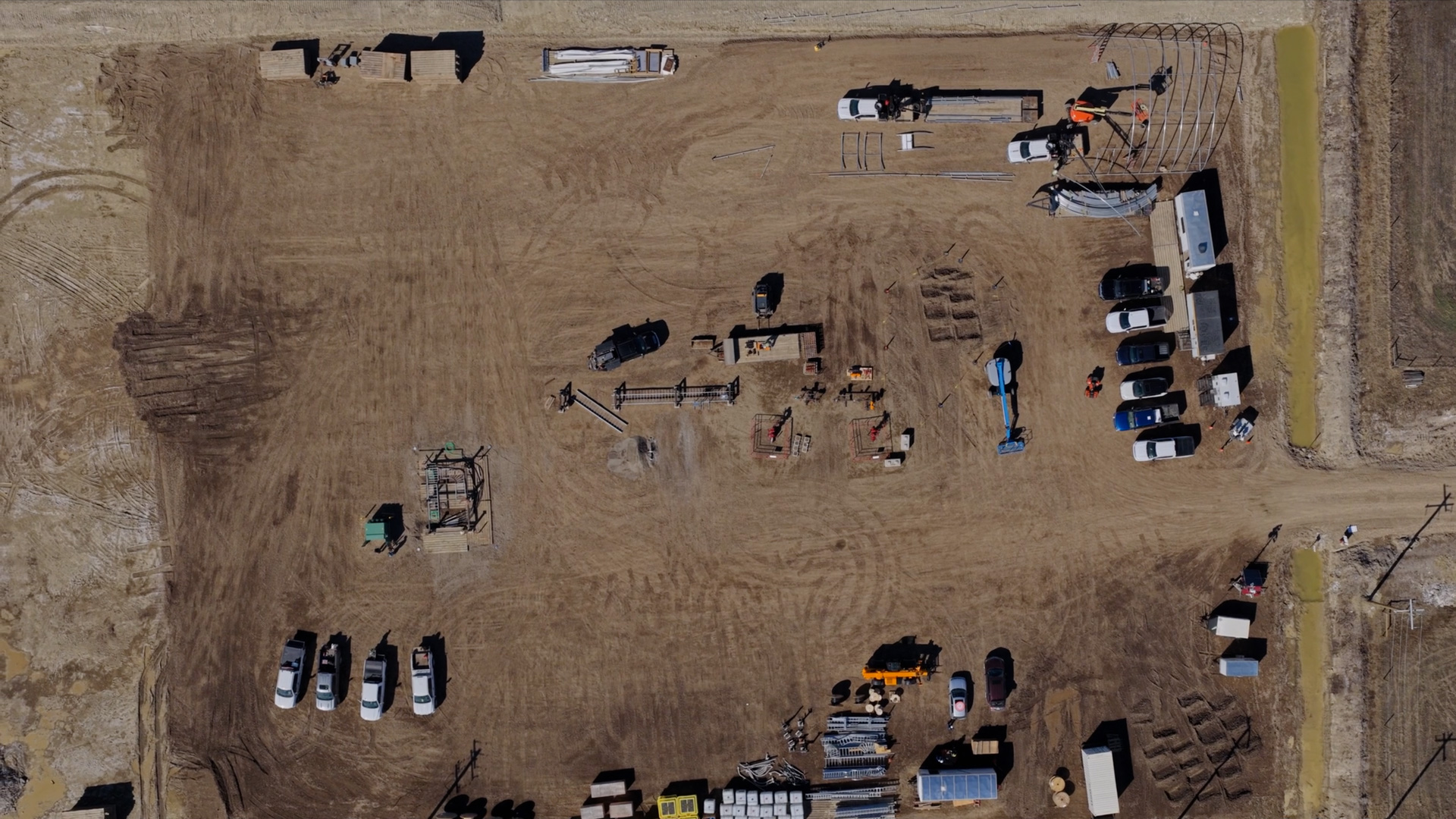 Top-down aerial of the E3 Lithium demonstration facility site near Olds, Alberta, with site trailers, laydown areas and crew vehicles on the graded pad