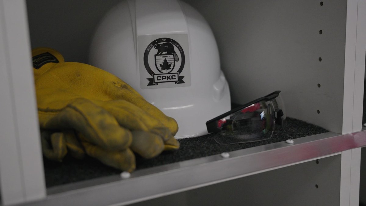 A CPKC hard hat, gloves and safety glasses on a shelf inside a response trailer
