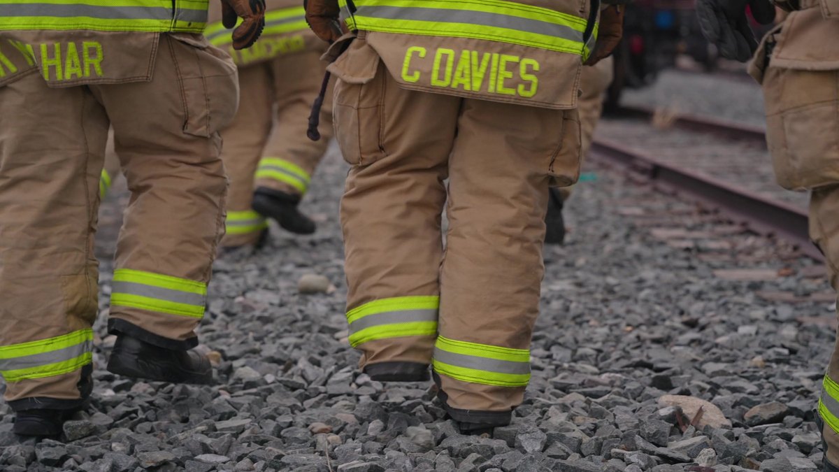 Responders in turnout gear walking the ballast beside the track at CPKC HazMat Days