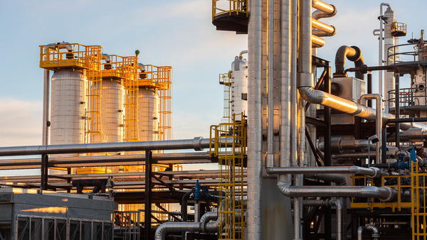 Gas processing facility with steel columns and pipe racks at sunset