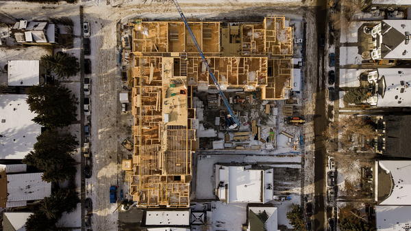 Aerial view of a multi-storey wood-frame building under construction in a residential neighbourhood