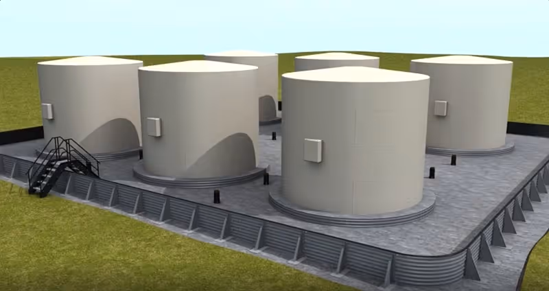 Six large white cylindrical storage tanks arranged on a concrete platform with railings.