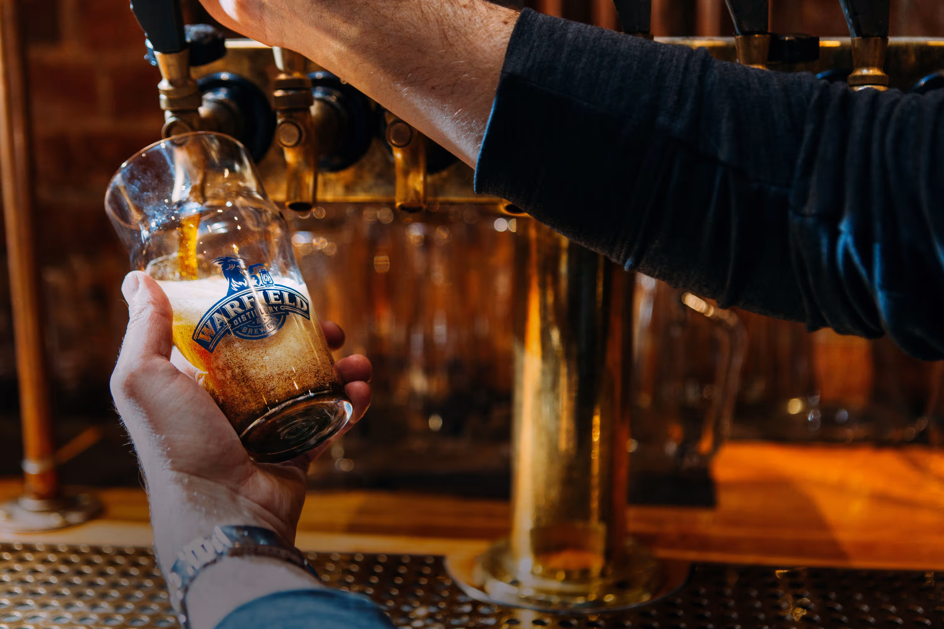 Hands filling beer glass from tap