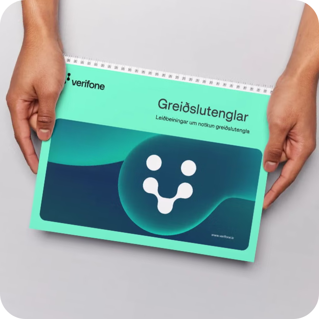 Hands holding a teal manual titled 'Greiðslutenglar' with Verifone logo and Icelandic text about payment connections.