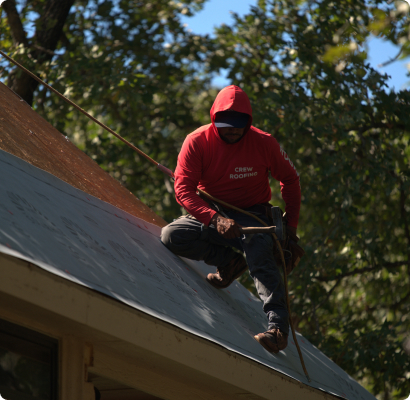 Roofer in a red sweater on top of a roof.