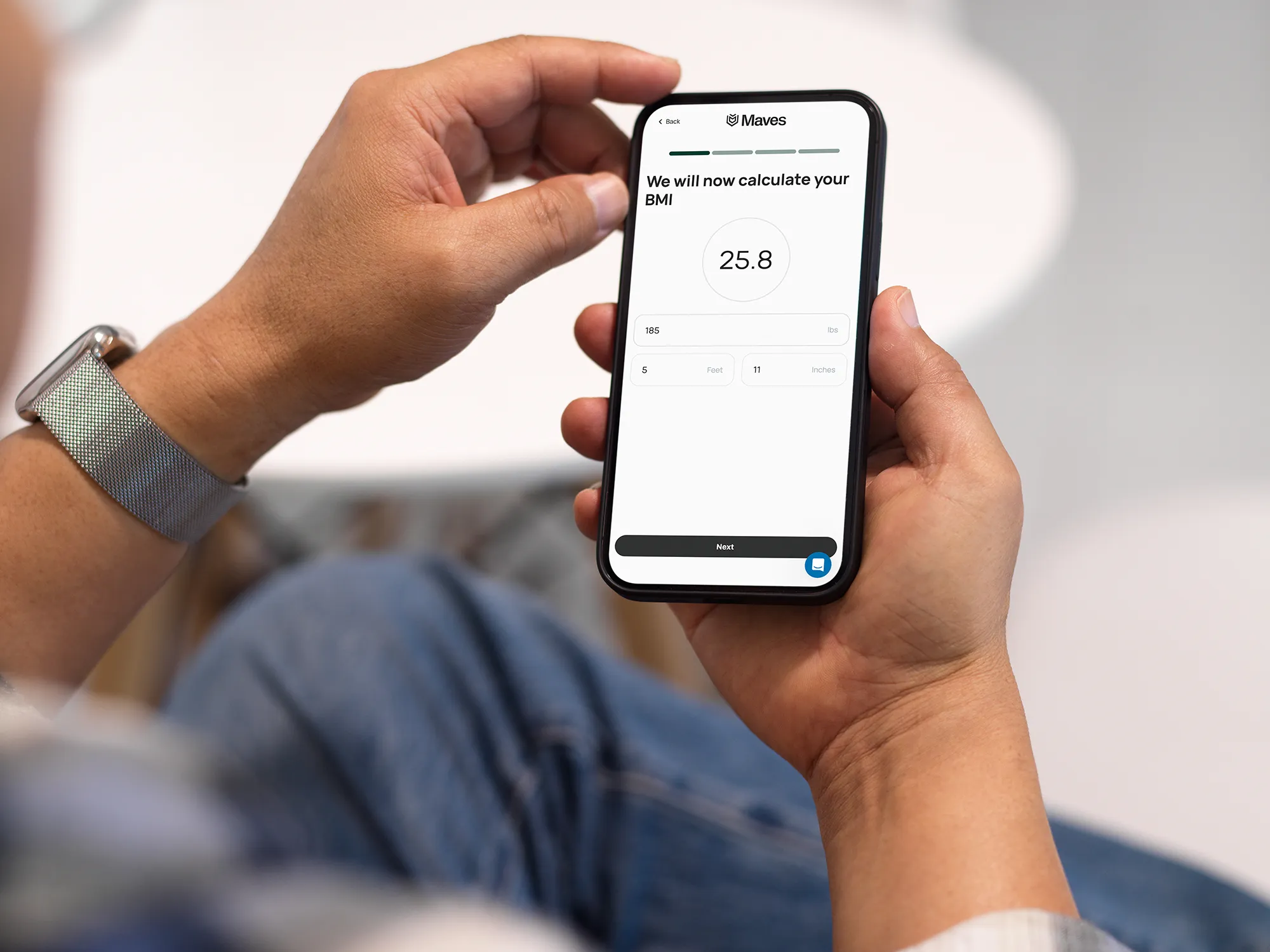 Person holding smartphone displaying BMI calculator with weight 185 lbs and height 5 feet 11 inches.