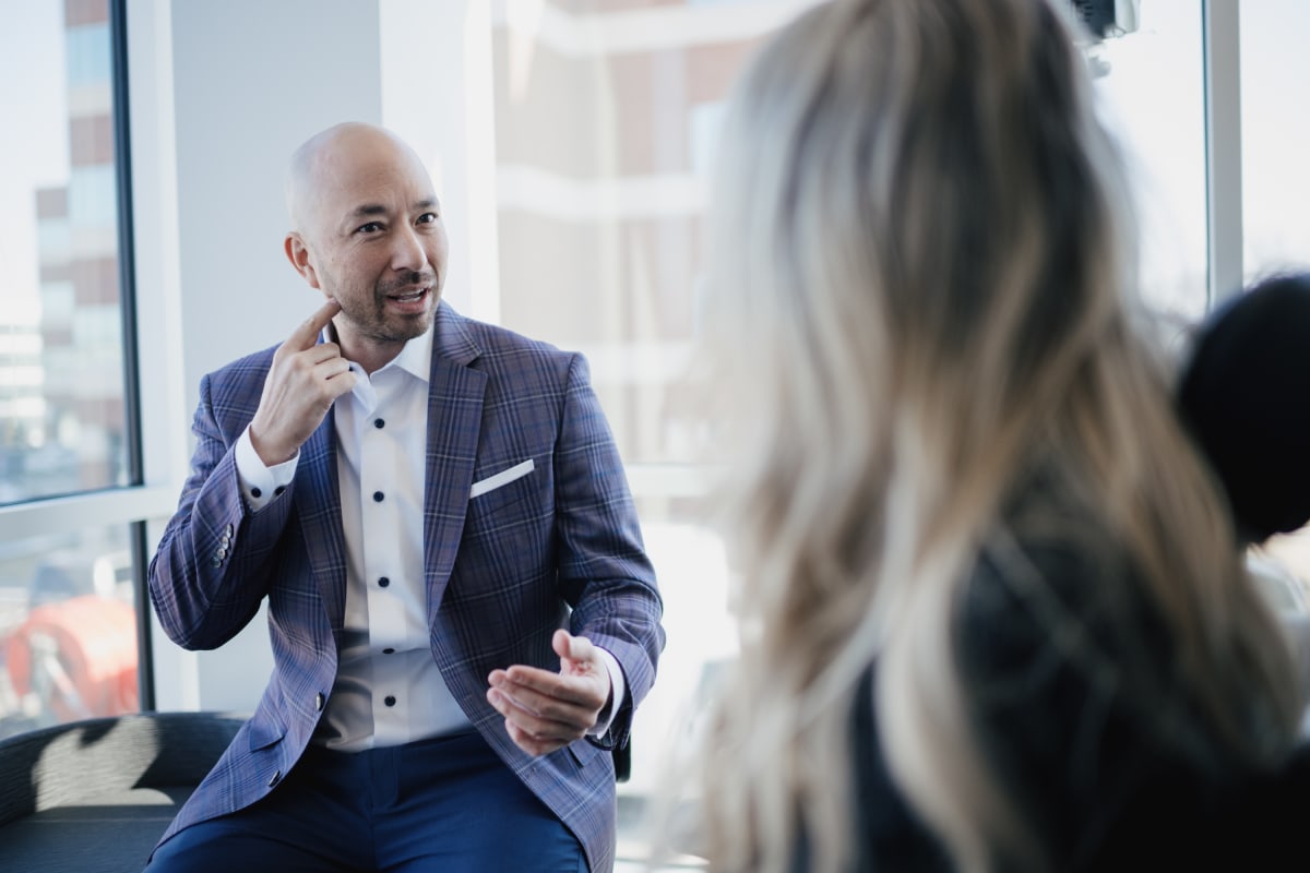 Male dentist in blue suit speaking with female patient in modern dental office