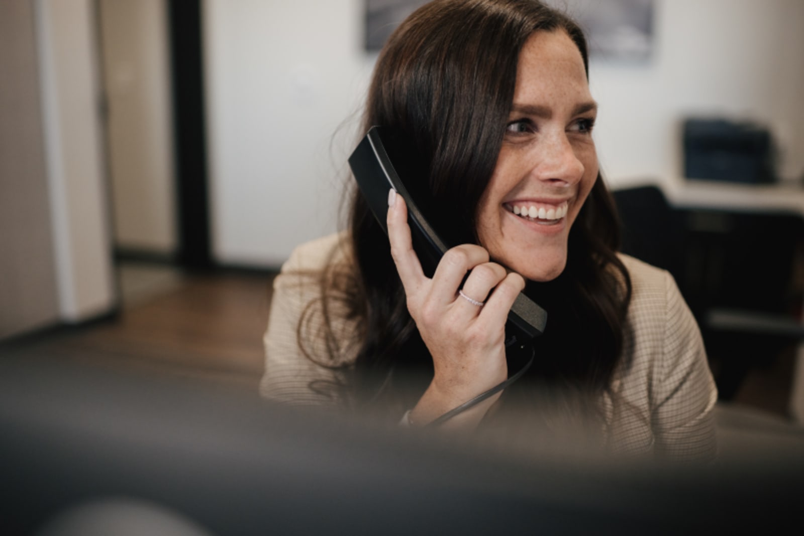 Woman smiling while talking on phone in a dental office setting.