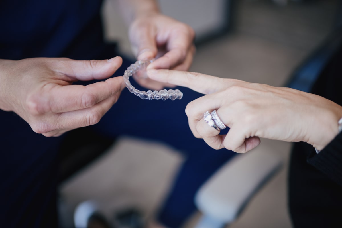 Two people examining a clear aligner tray during an Invisalign consultation.