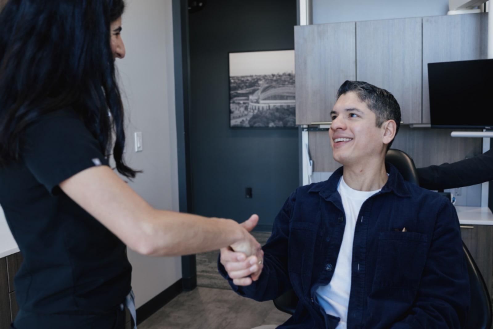Dental team member greeting a patient with a handshake in the office reception area.