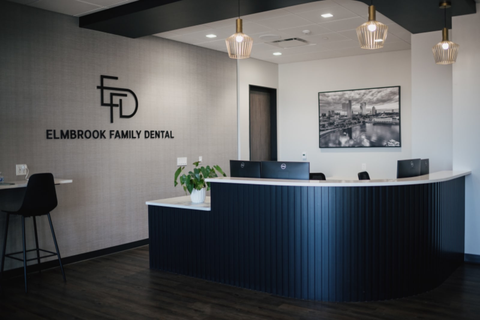 Modern dental reception area with dark blue desk and welcoming front entrance at Elmbrook Family Dental.