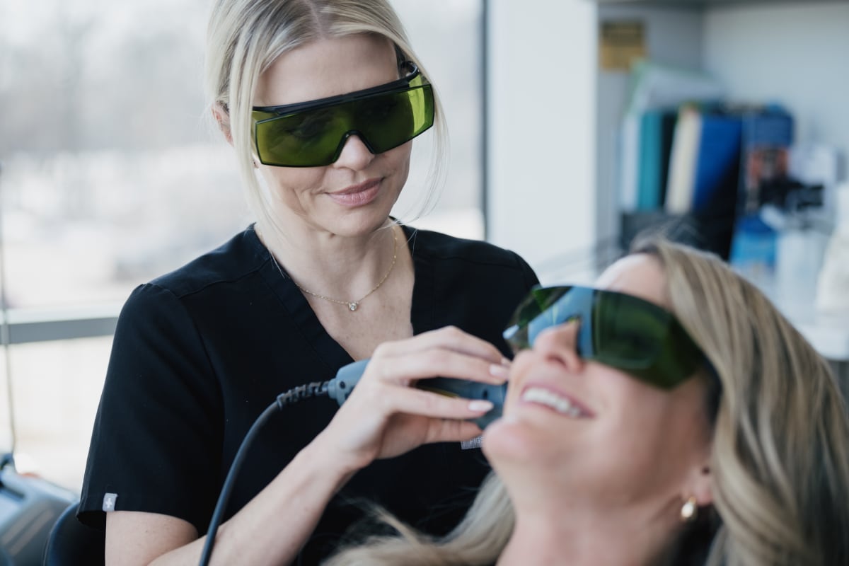 Dentist adjusting virtual reality headset on patient during TMJ treatment demonstration.