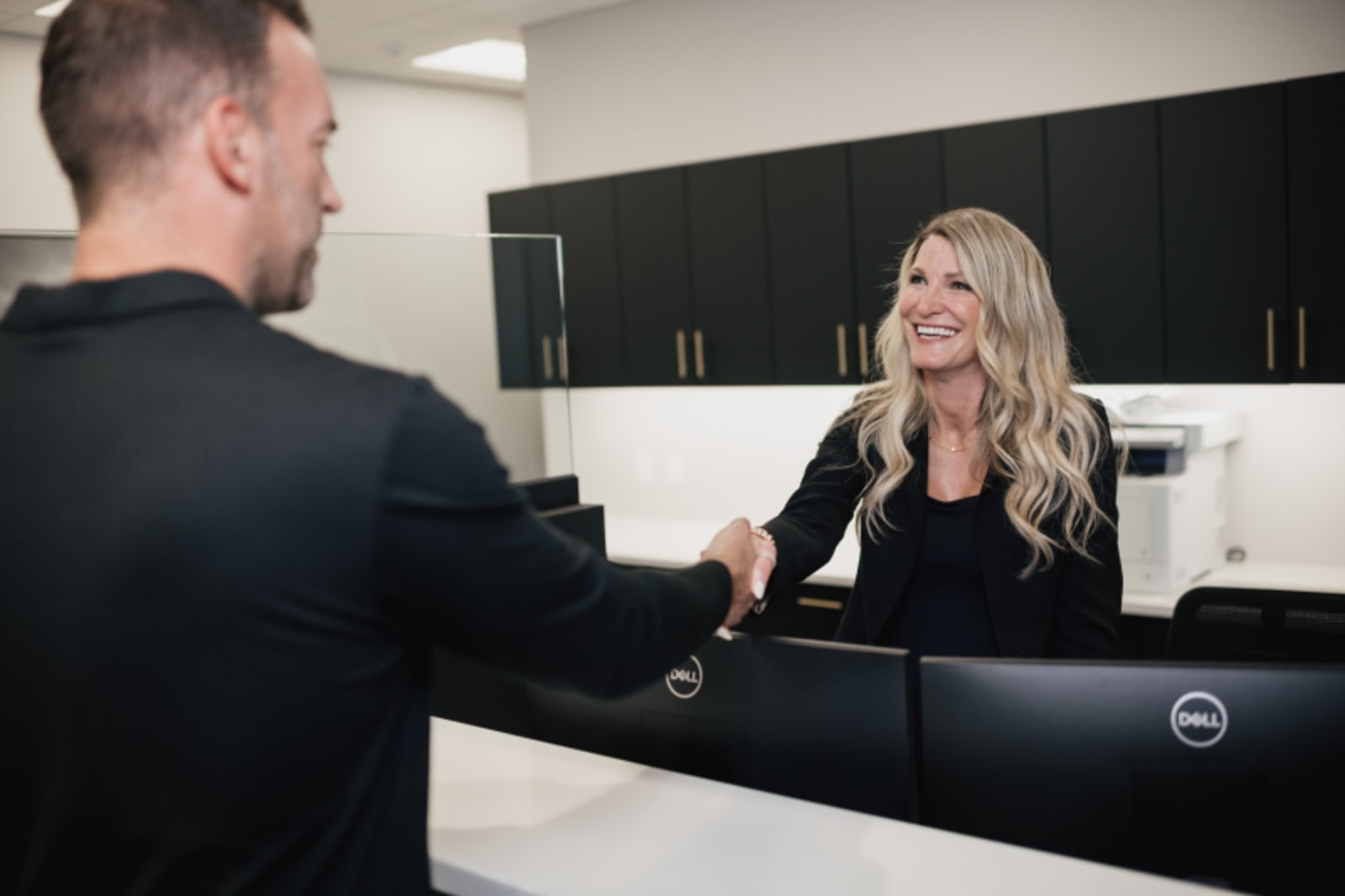 Female dentist discussing treatment options with male patient at reception desk.