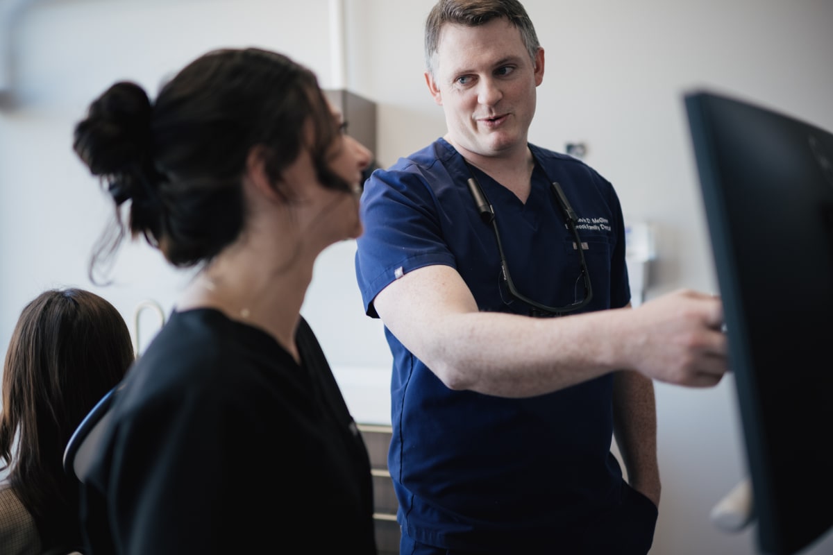 Dentist explaining sleep apnea treatment options to a patient in a clinical setting.