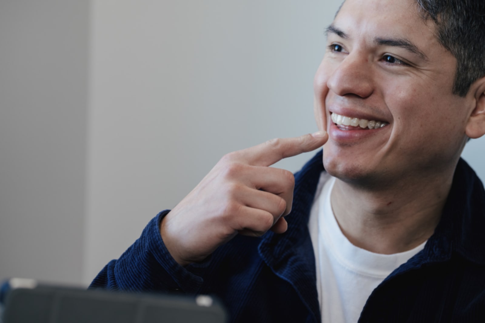 Man smiling while touching his face and jaw in a clinical setting.