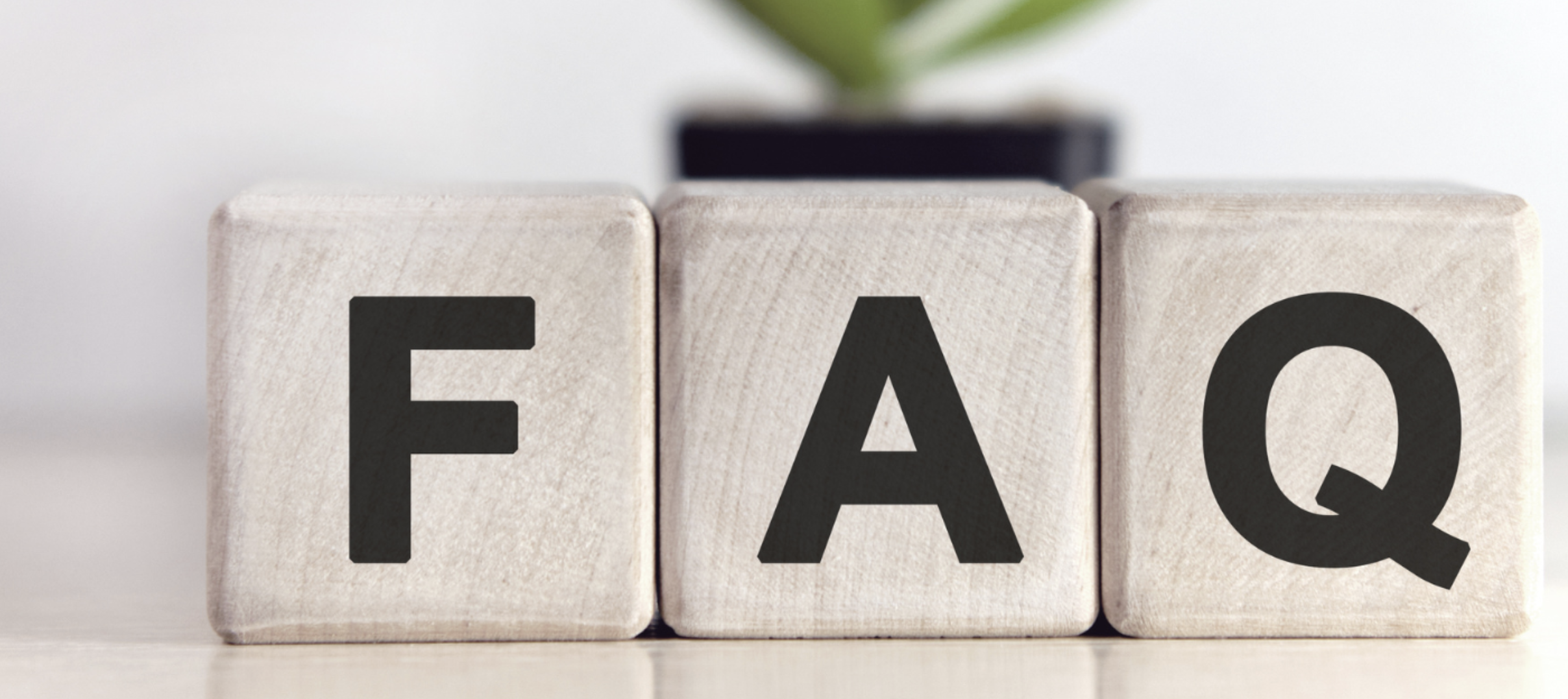 Wooden blocks with black letters spelling FAQ on a light surface with blurred background.