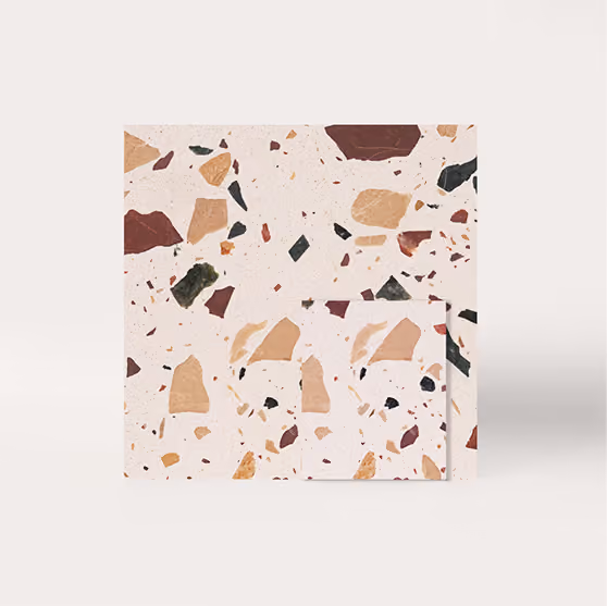 Square terrazzo tile with pink, brown, green, and beige stone chips on a light background.