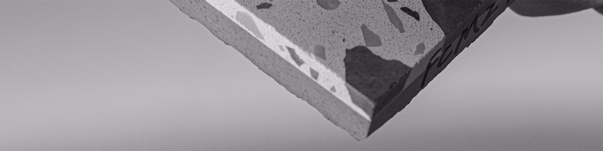 Close-up of terrazzo tile corner with mixed stone fragments in grayscale.