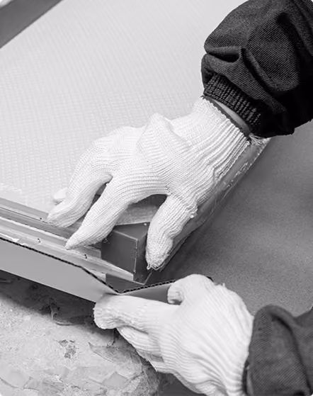 Hands wearing white gloves installing or adjusting a textured wall panel or tile.