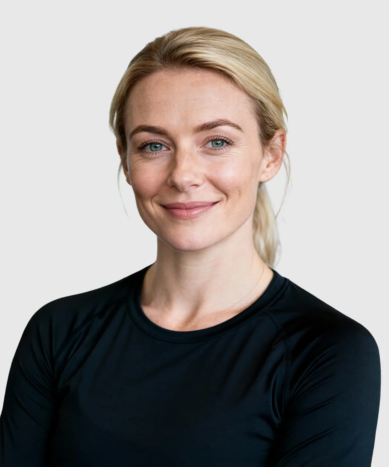 Close-up of a smiling blonde woman wearing a black athletic shirt in a gym setting.