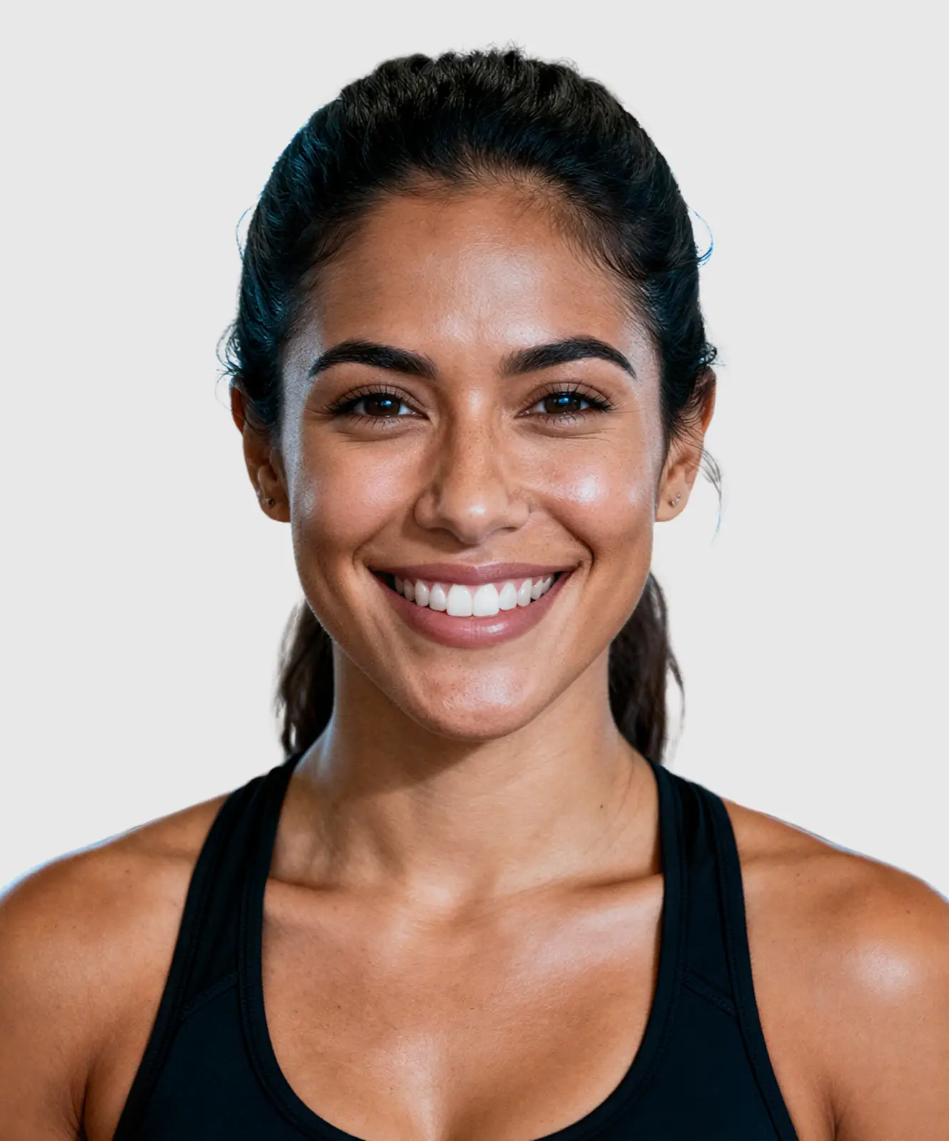 Smiling young woman in a black workout tank top at the gym with exercise machines in the background.