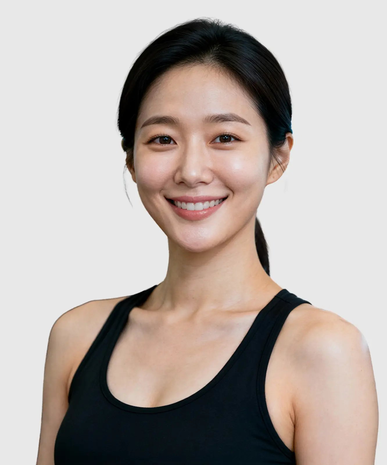 Smiling woman in black tank top standing in a gym with exercise equipment in the background.