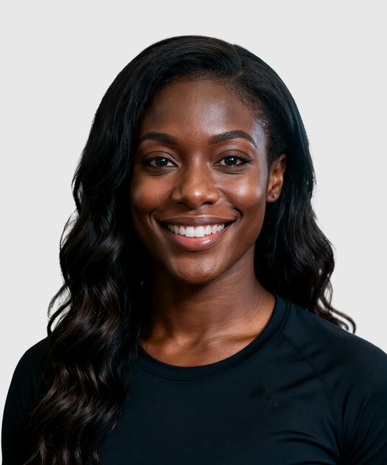 Smiling woman with long wavy hair in black athletic shirt at a gym.