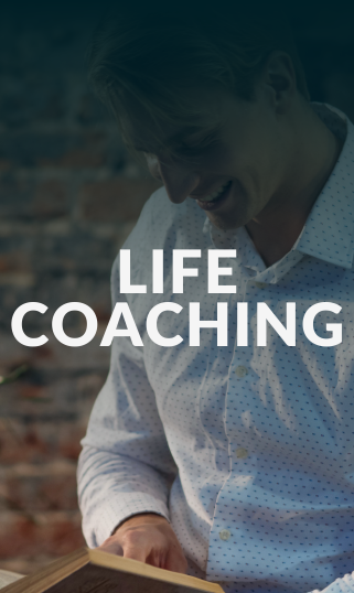 Smiling man in a white shirt reading a book with text 'LIFE COACHING' overlayed.