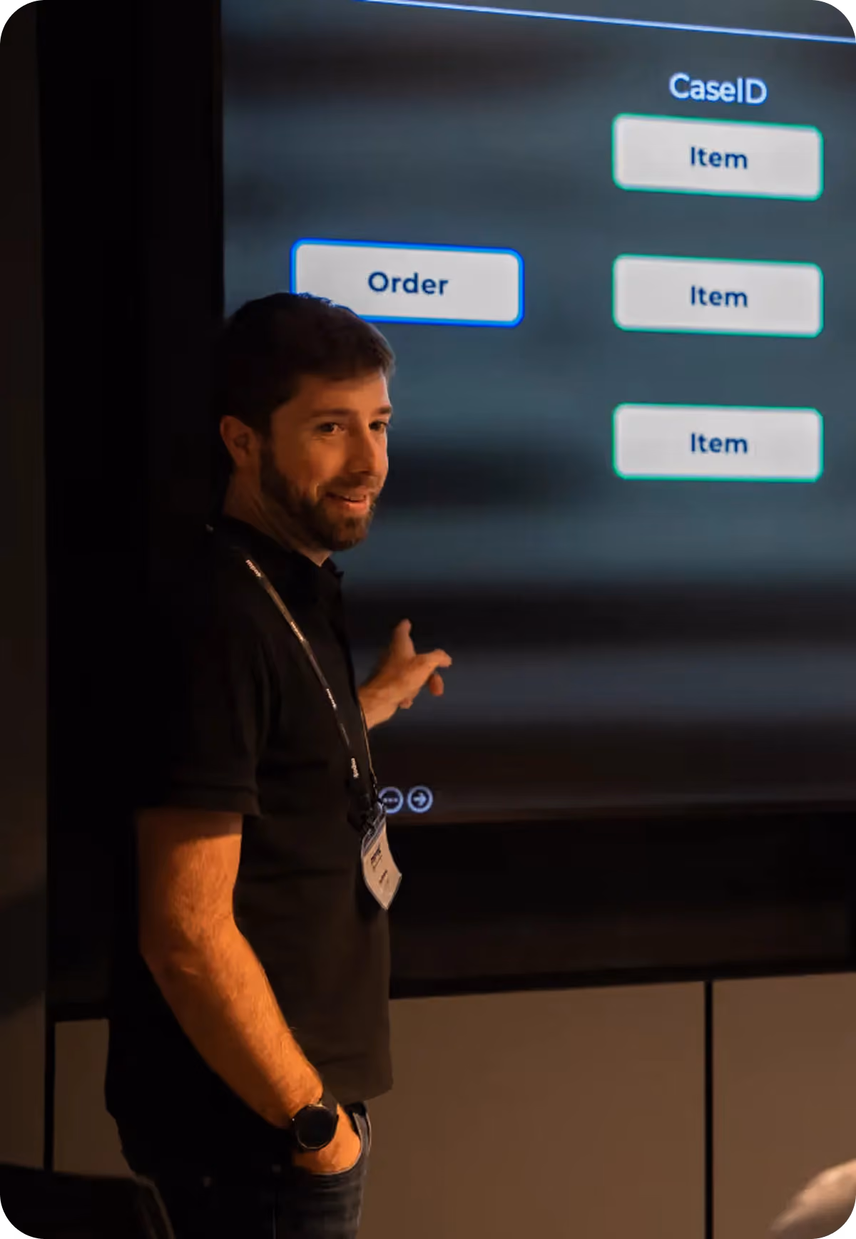 Man in black shirt pointing to a screen showing boxes labeled Order and Item in a presentation.