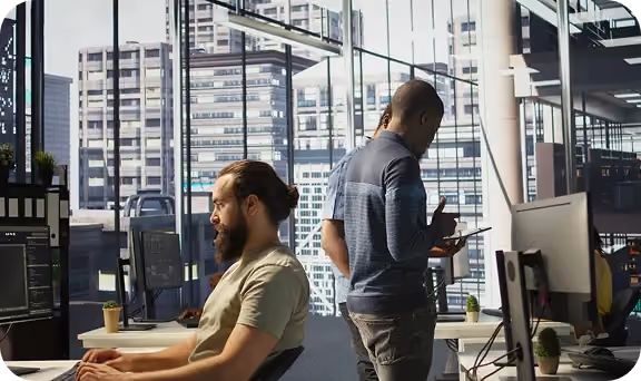 Two men working in a modern office with large windows showing city buildings outside.