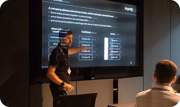 Man presenting a slide about purchase order concepts to an audience in a dark room.