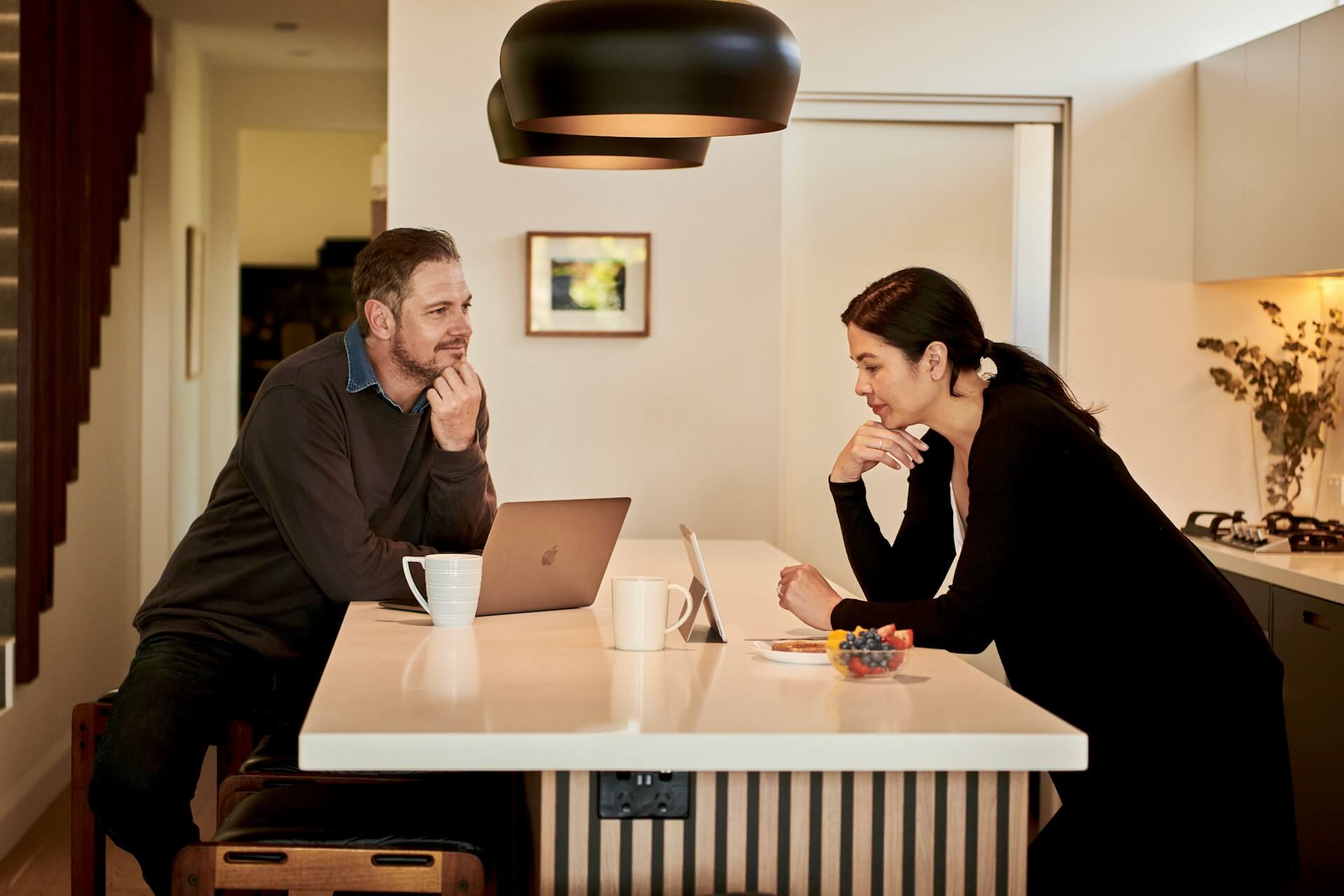 two people in kitchen reviewing documents on iPad and Macbook