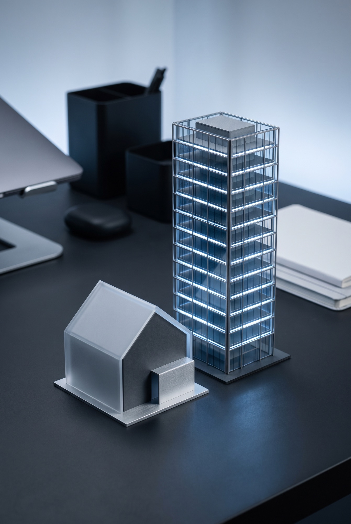 Modelhuis naast een verlichte glazen kantoortoren op een bureau, als beeld voor eenmanszaak tegenover BV