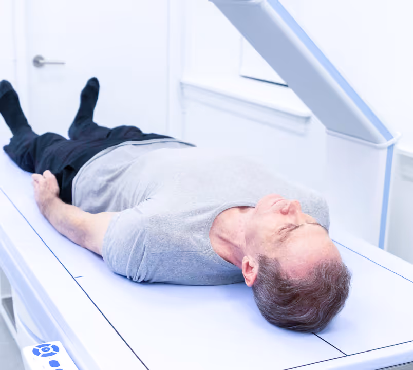 Man lying on a medical scanning table in a clinical room, preparing for a scan.