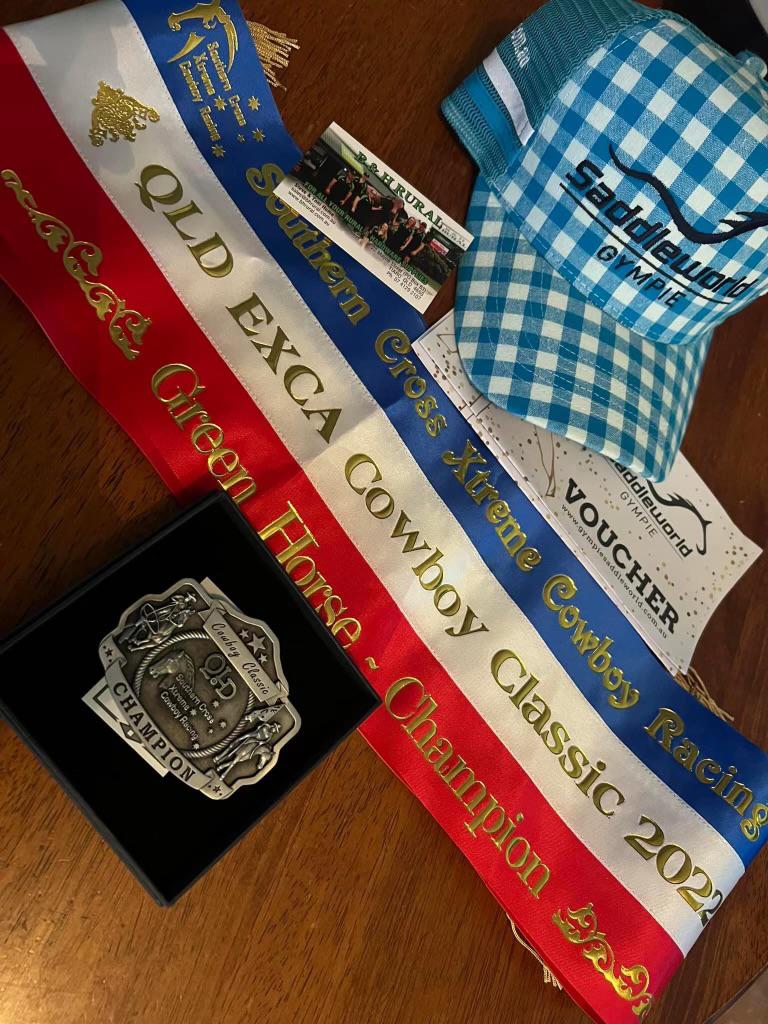 Commemorative belt buckle award displayed with ribbons and memorabilia from the QLD EXCA Cowboy Classic 2022 event.