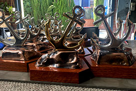 Gloved hand handling finished metal recognition buckle during production