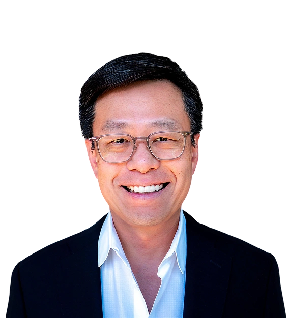 Smiling middle-aged man with black hair and glasses wearing a white shirt and dark blazer.