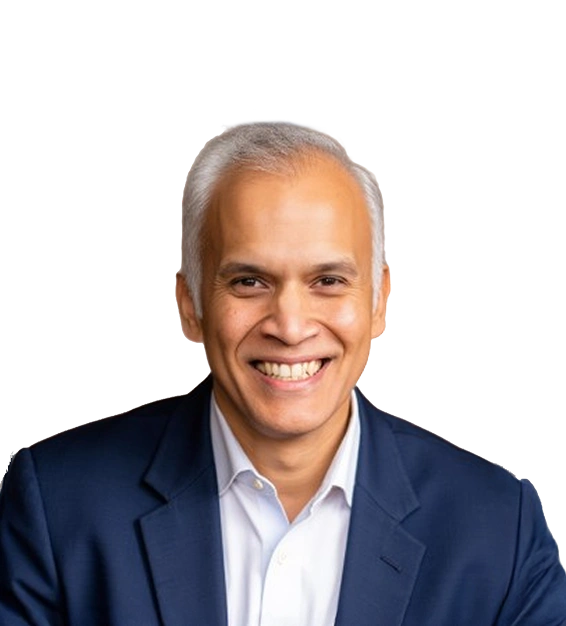 Smiling man with gray hair wearing a navy blue suit and white shirt against a transparent background.