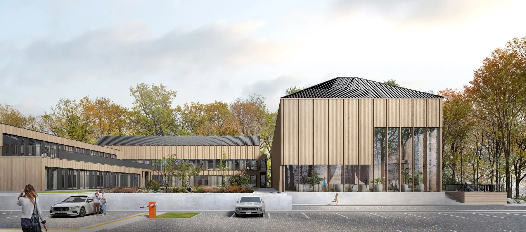 Modern wooden building with large glass windows surrounded by trees and a parking lot in front.
