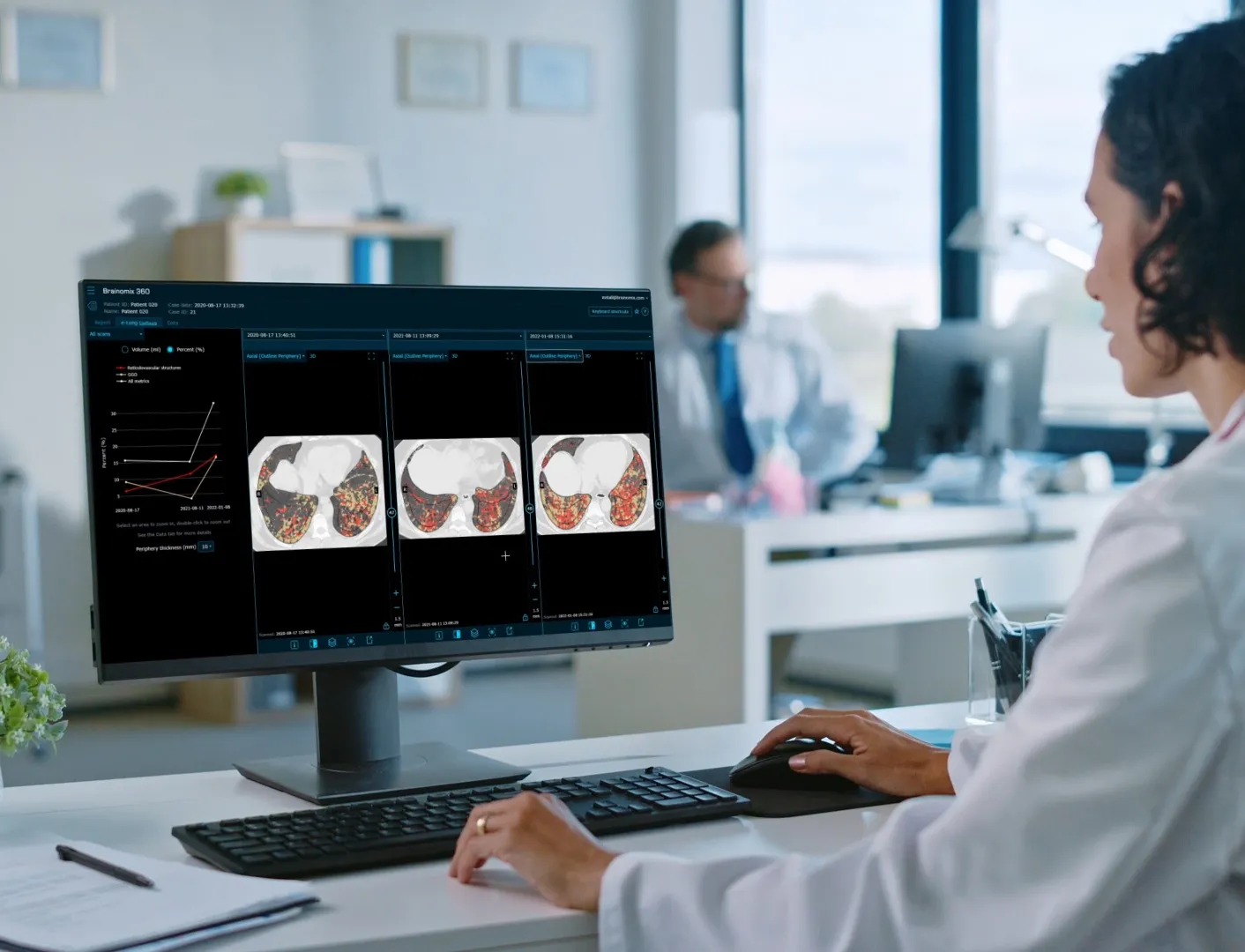 Medical professional reviewing lung scan images and data on a computer screen in an office setting.