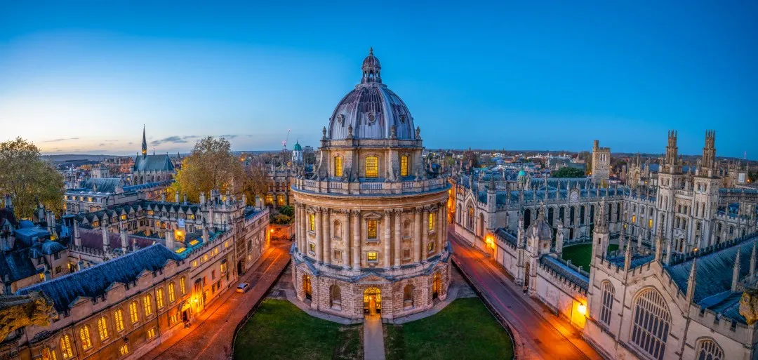 Evening view of Radcliffe Camera and surrounding historic buildings in Oxford under a clear blue sky.