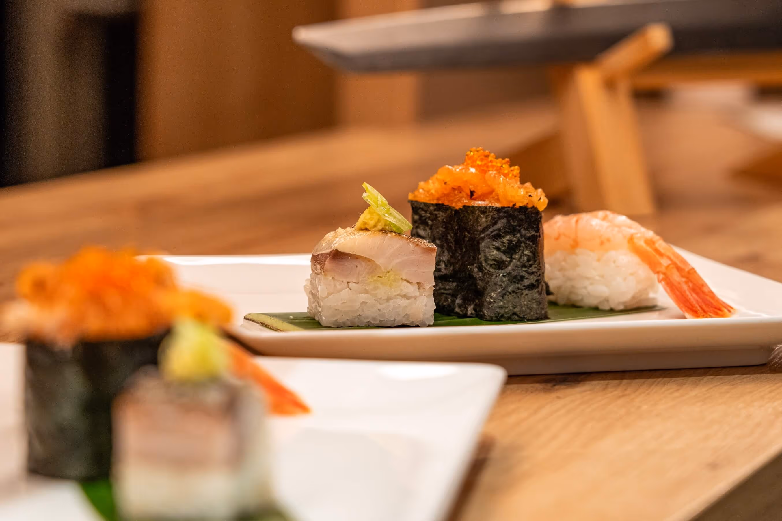 Close-up of various sushi pieces, including shrimp nigiri, fish nigiri with freshly grated wasabi and sushi with fish roe on white plates at Nashi Dining at Wenigemarkt in Erfurt.